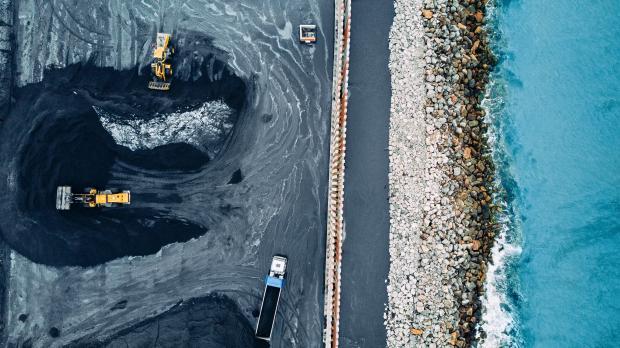An aerial view of trucks moving coal by the coast