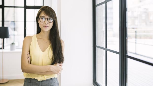 A young professional stands in an open plan office