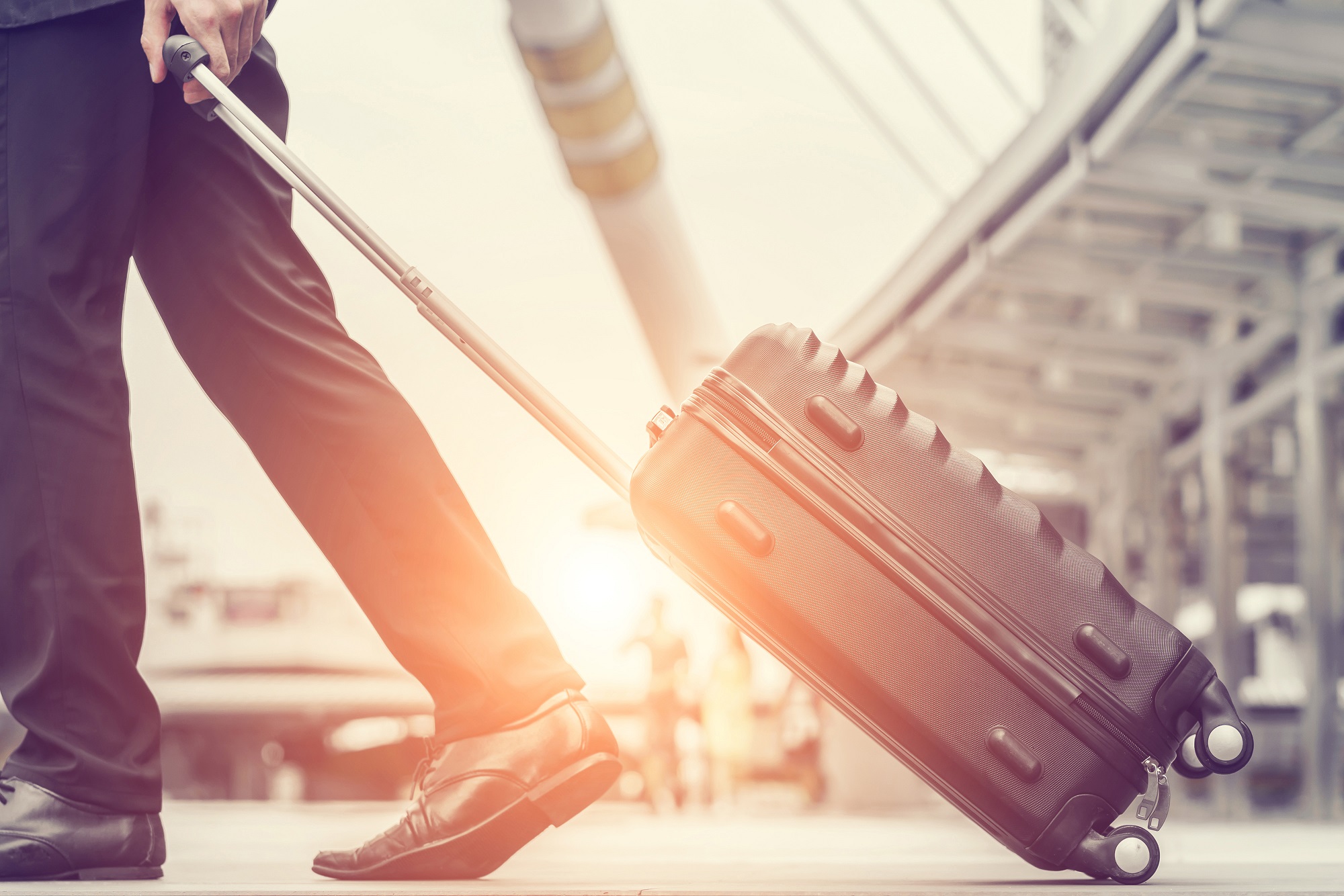 pulling suitcase at airport - expats employee benefits Howden