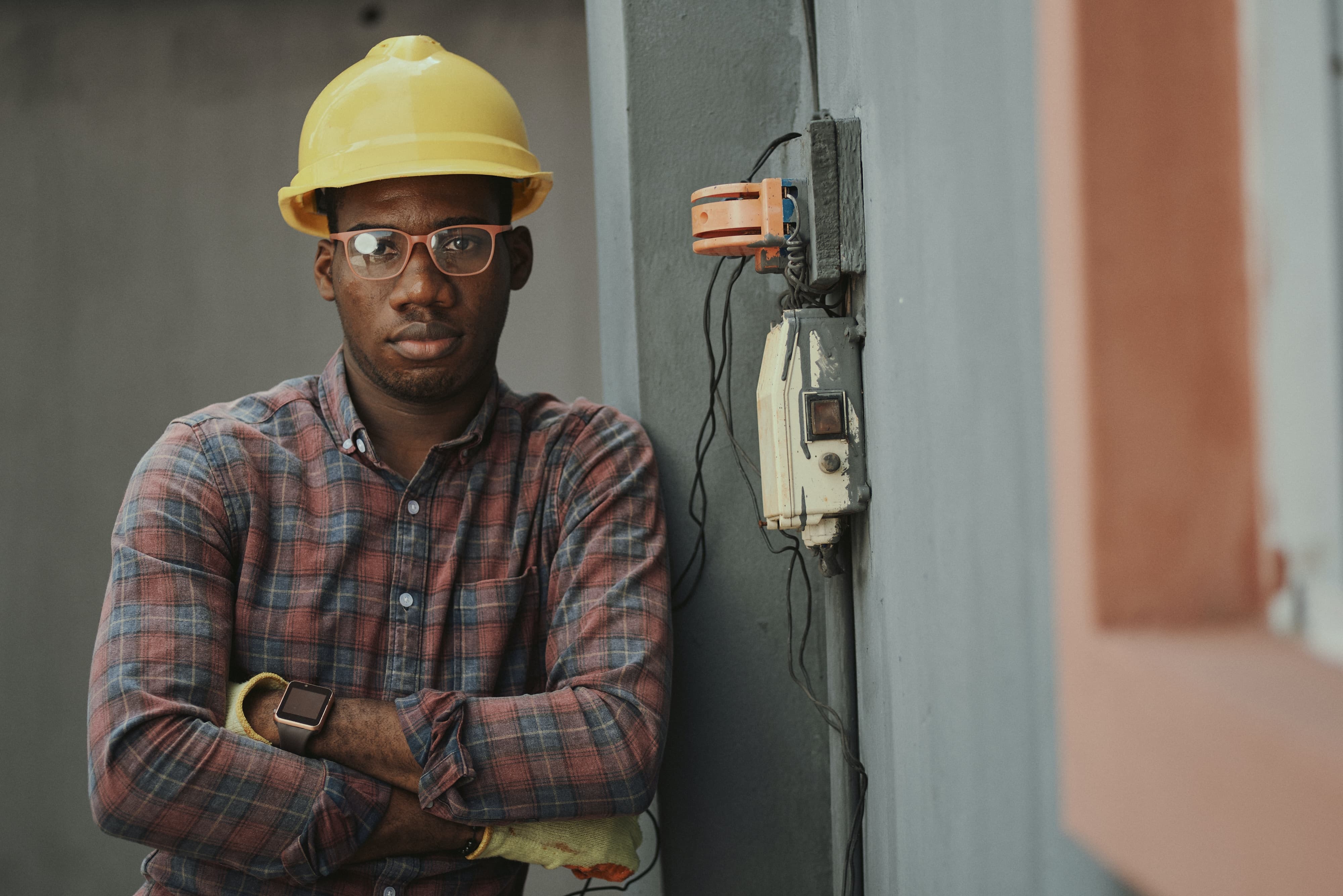 Black construction worker in hard hat leaning against wall