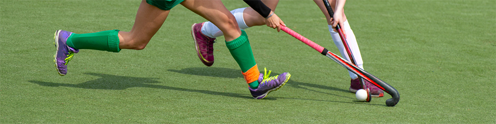 2 hockey players with sticks tackling the ball