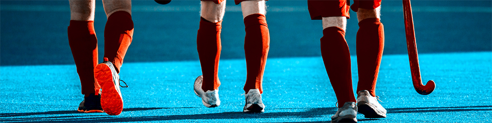 Three hockey players in red shorts and socks one as a hockey stick