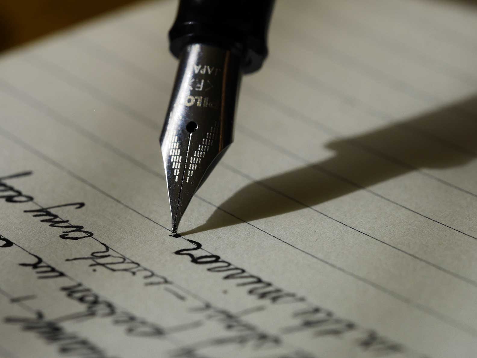 A fountain pen being used to write on lined paper