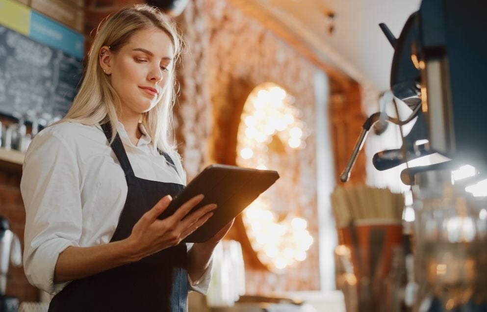 young barista checking tablet