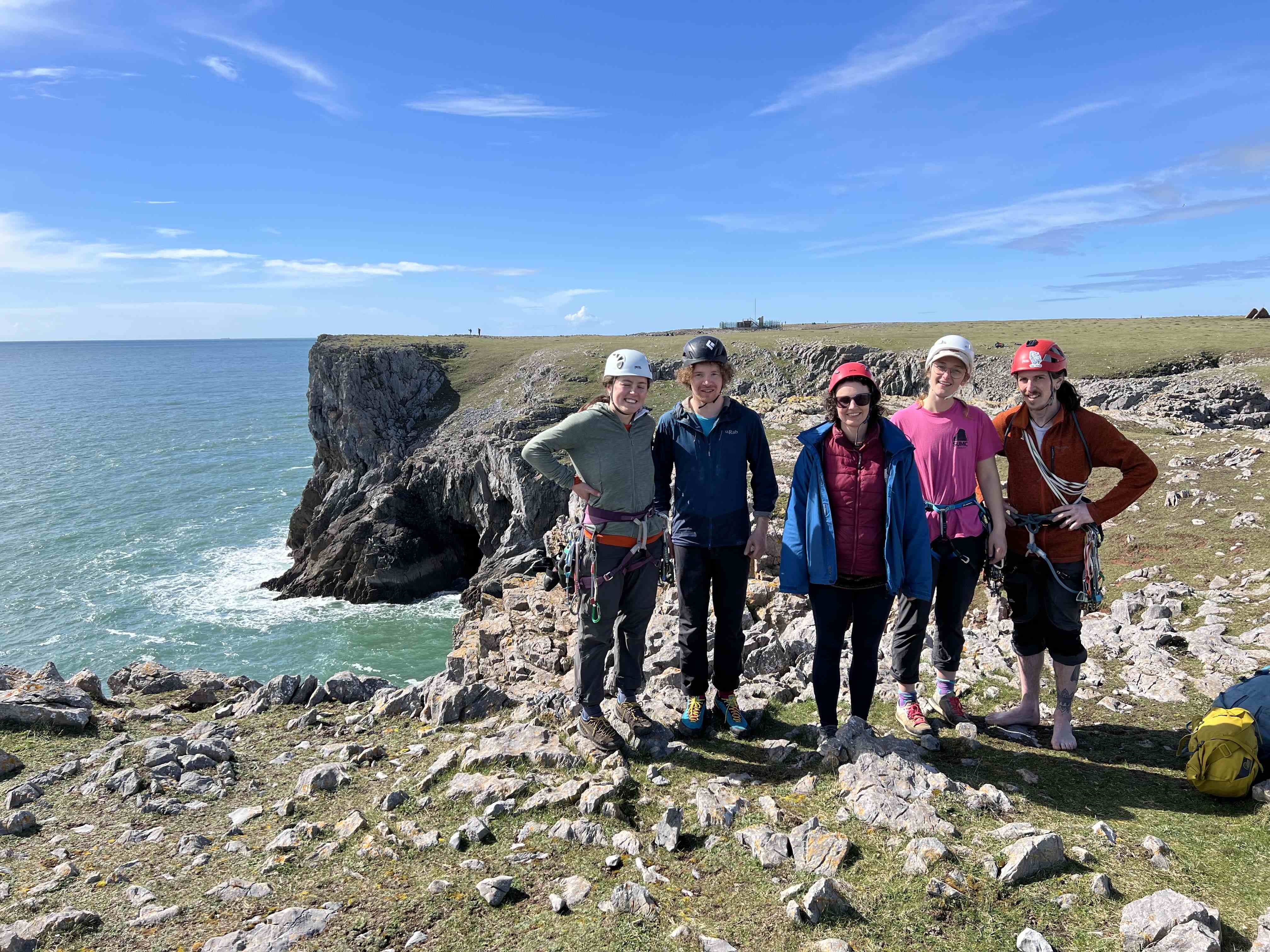 Group of mountaineers on a cliff edge smiling in the sun