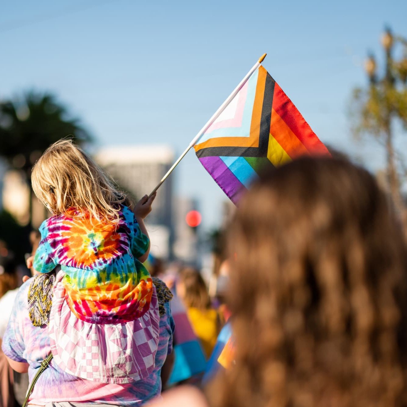 Young girl wearing rainbow T shirt, waving a rainbow flag