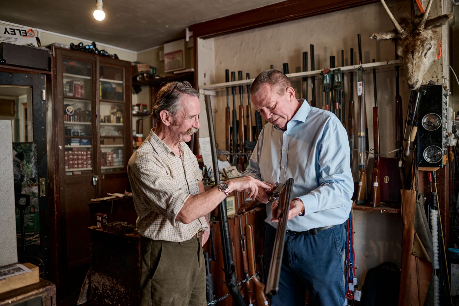 two men inspecting a shot gun