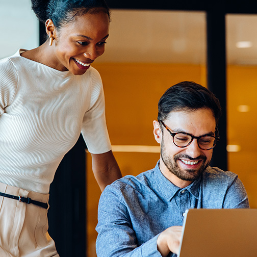 Man and woman looking at laptop in work environment