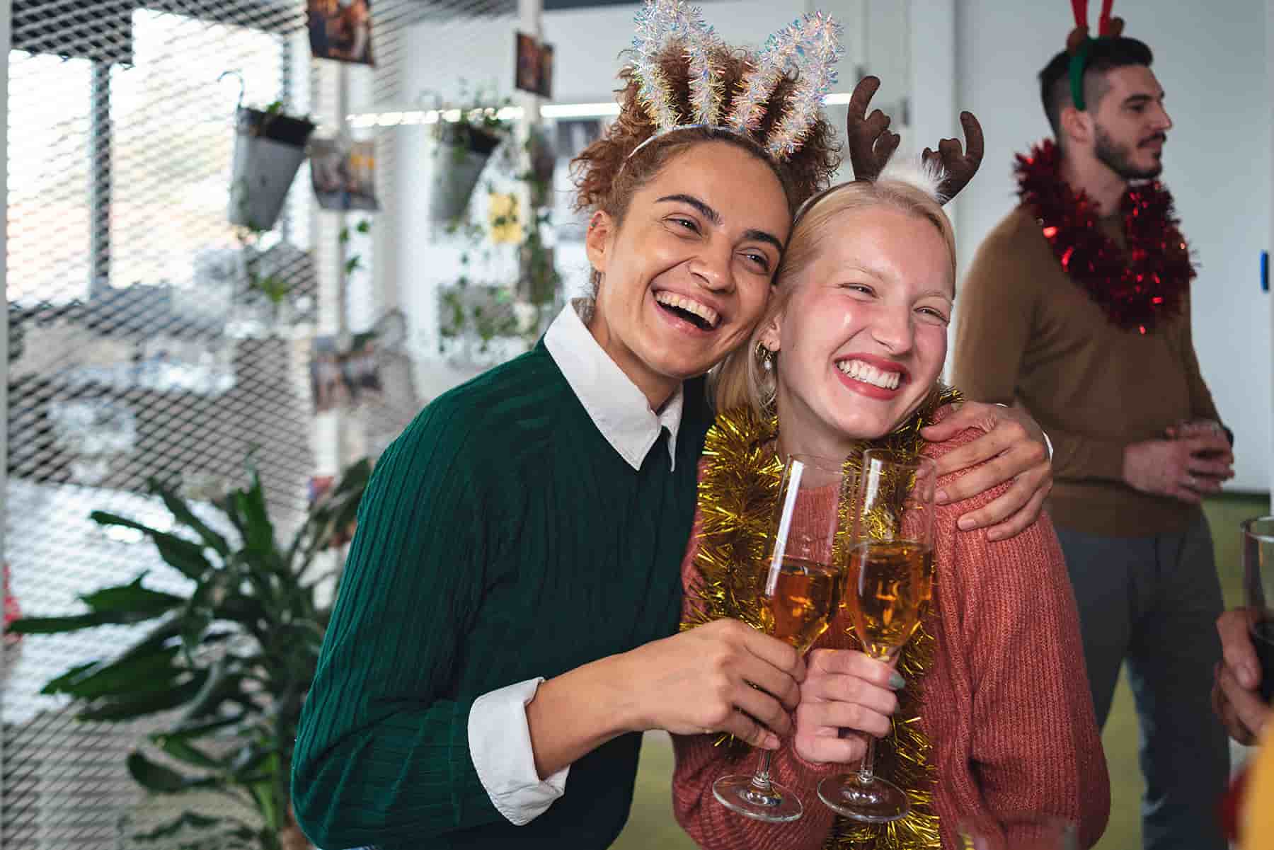 Two women enjoying a laugh together at a work Christmas party