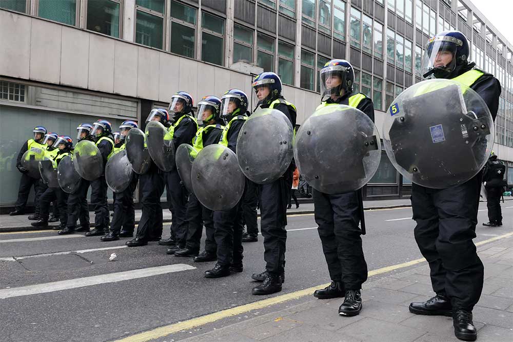 UK riot police with shields and wearing helmets up lined up ready