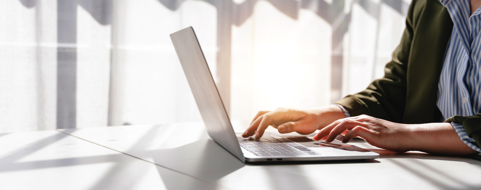 A person focused on typing on a laptop computer, with hands positioned over the keyboard.
