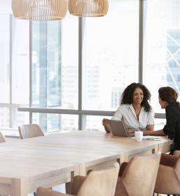 Two business women have a meeting in a brightly lit modern office
