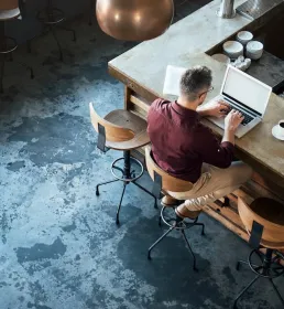 A young professional sits in a coffee shop working on his laptop