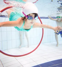 Girl swimming through hoop underwater