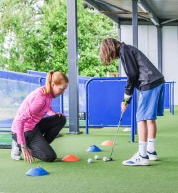 Pro golfer teaching younger golfer to putt