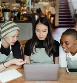Three people at laptop in cafe