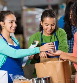 People putting food donations in paper bag