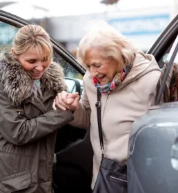 Charity worker helping older person out of car