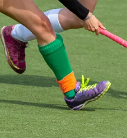 2 hockey players with sticks tackling the ball