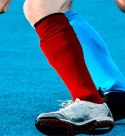 Two men playing hockey one with red socks one with light blue socks