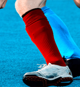 Two men playing hockey one with red socks one with light blue socks
