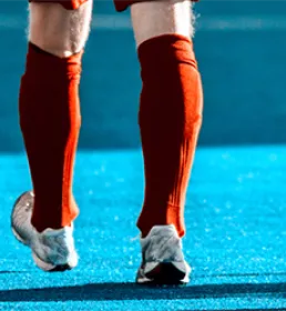 Three hockey players in red shorts and socks one as a hockey stick
