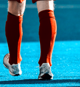 Three hockey players in red shorts and socks one as a hockey stick