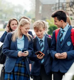 Pupils in uniform walking looking at phones