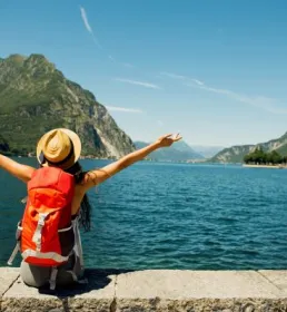 Young person happily sat on wall by ocean