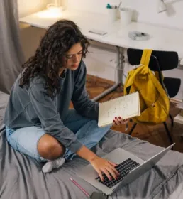 Student sat on bed at laptop