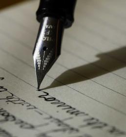 A fountain pen being used to write on lined paper