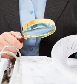 man with magnifying glass looking at documents