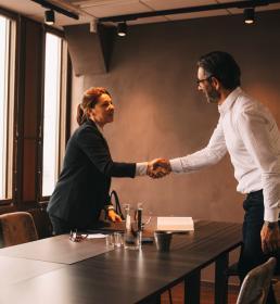 Businessman and woman shaking hands over a table