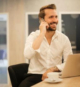 Businessman smiling and talking on the phone in front of laptop