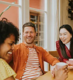 Three friends drinking coffee and smiling