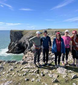 Group of mountaineers on a cliff edge smiling in the sun