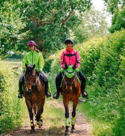 Horses and riders in high vis hacking through countryside
