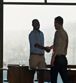 2 businessmen shaking hands in light filled office