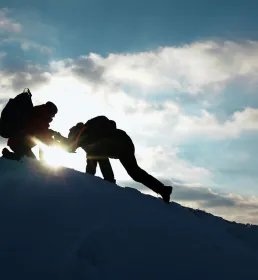 Travelers climb together up mountain.