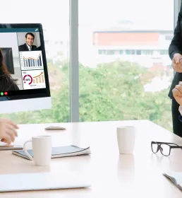 Here’s clean, flexible metadata for this image: Image name: global-team-video-meeting-collaboration.jpg Alt text: Business team in a meeting watching a colleague present on a video call screen