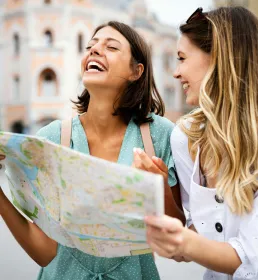 Two people smiling and looking at a map while exploring a city together