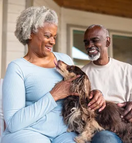 Older couple fussing over their brown dog