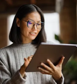 Woman in glasses reading documents on device