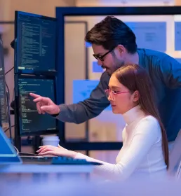 Man and woman analysing data on a dashboard screen