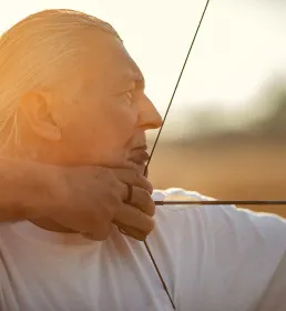 Mature man playing archery in sun glow