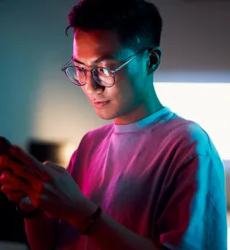 Asian man reviewing his phone in neon lit office