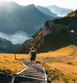 Hiker walking down steps through valley and mountain landscape