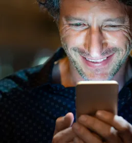 Man smiling, looking at his phone