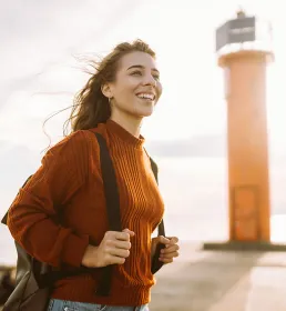 Young female hiking in front of a lighthouse