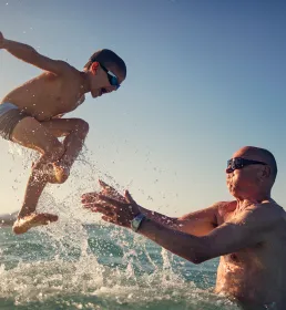 Grandad catching boy jumping into sea